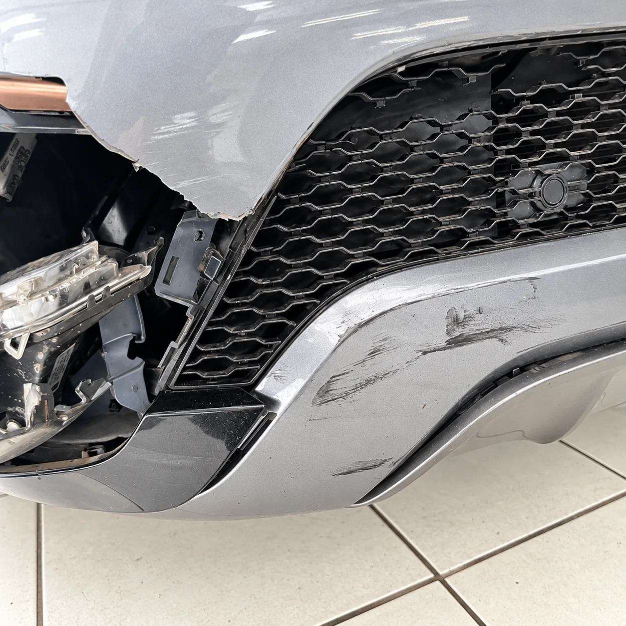 Para-choque dianteiro destruído e farol desalojado do Range Rover Evoque 2020 após a colisão com motocicleta